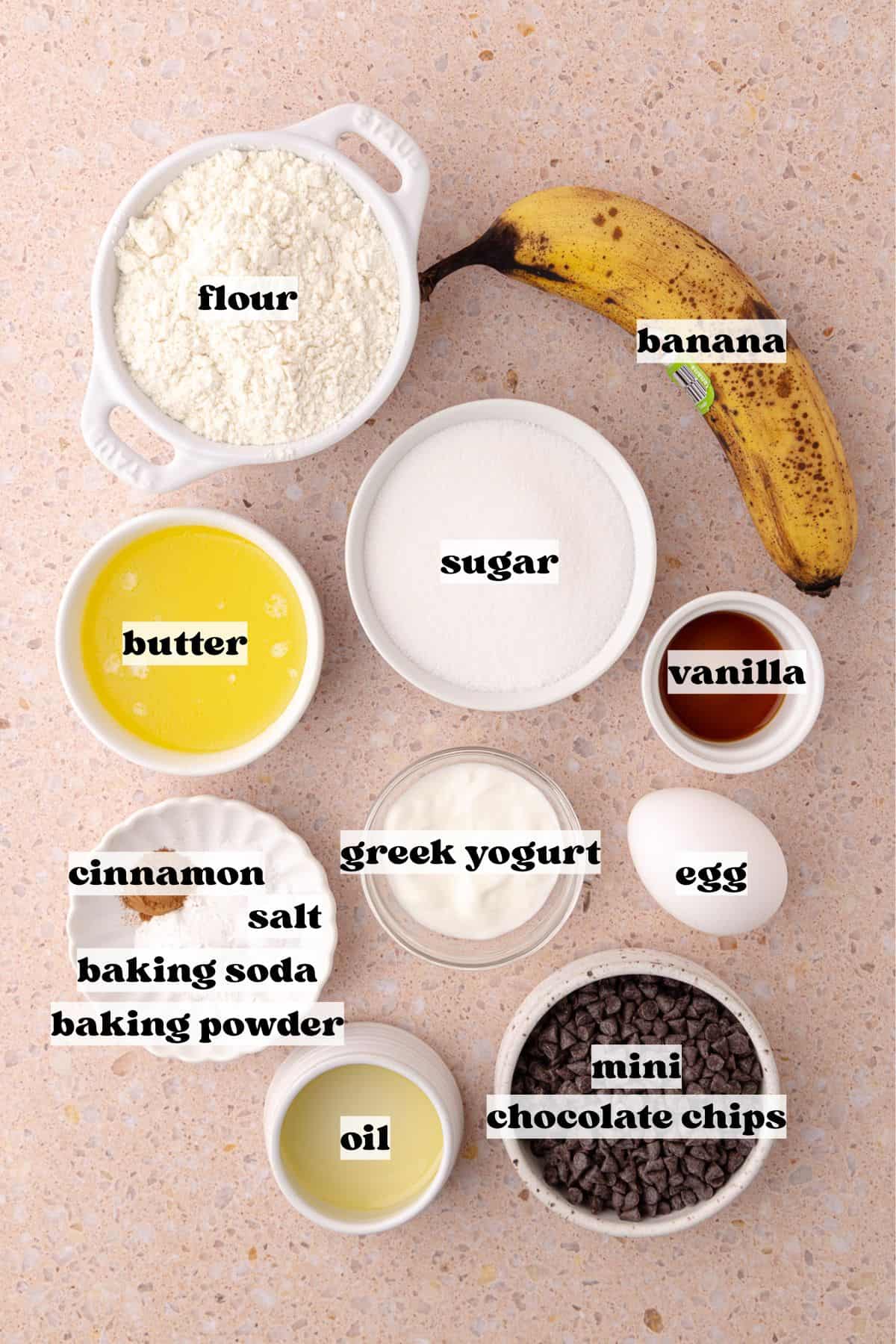 Small batch banana muffins ingredients, which include flour, cinnamon, baking powder, baking soda, salt, banana, melted butter, oil, greek yogurt, egg, vanilla and mini chocolate chips.