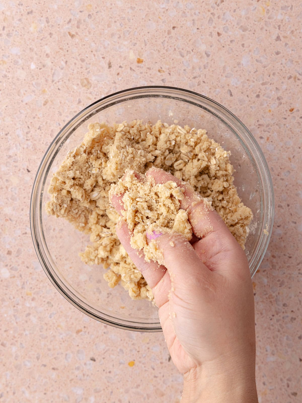 A person's hand holding oatmeal streusel crumble.