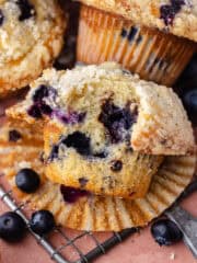 Bakery-style blueberry chocolate chip muffins with streusel topping sitting on a wire rack feature photo.