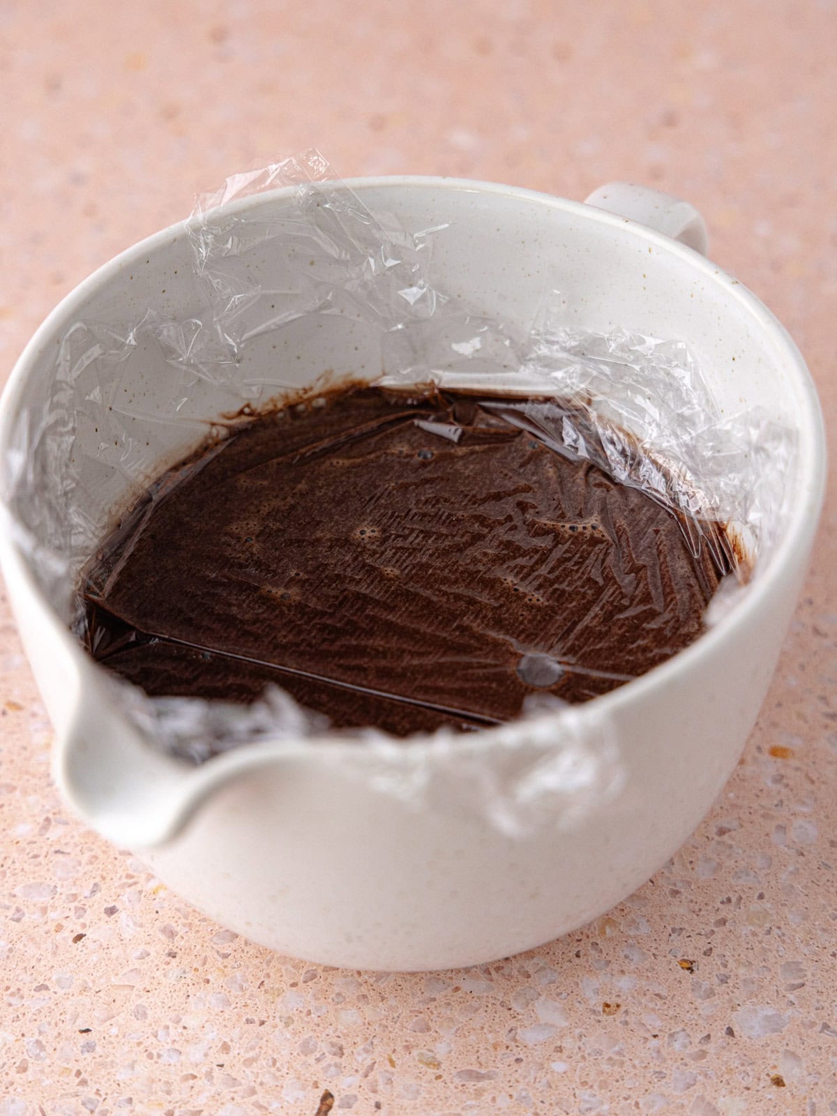 Plastic wrap is placed over chocolate ice cream base to prevent a skin from forming.