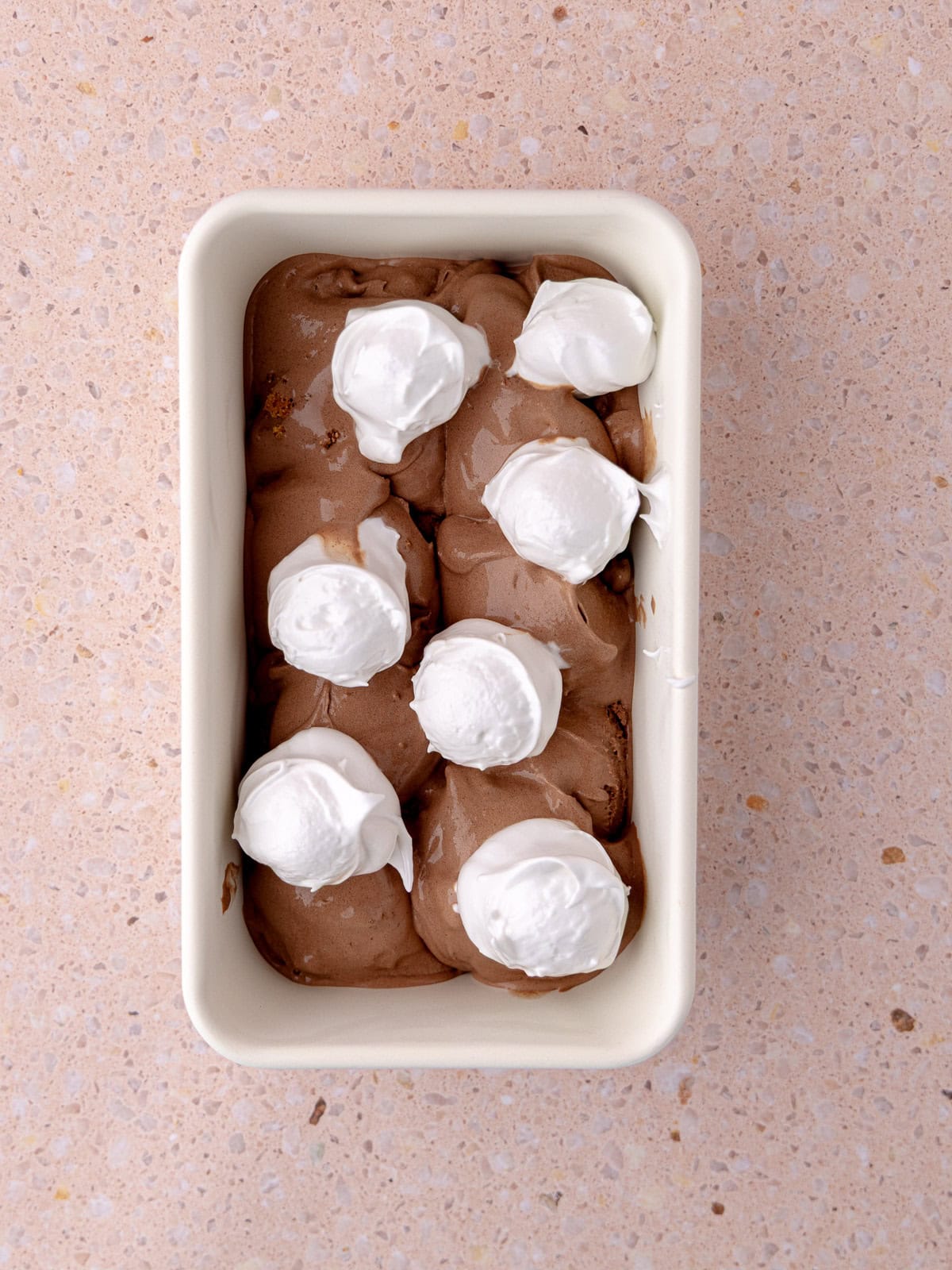 Chocolate ice cream and homemade meringue marshmallow are in a white loaf pan container.