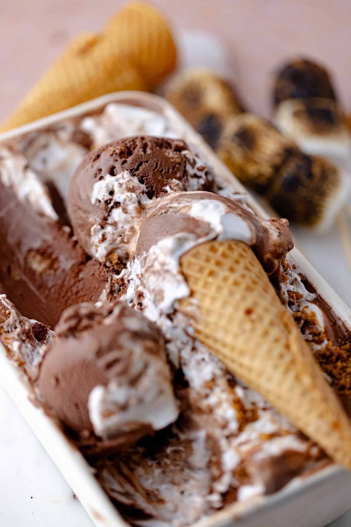 Scoops of chocolate s'mores ice cream are in a white container.