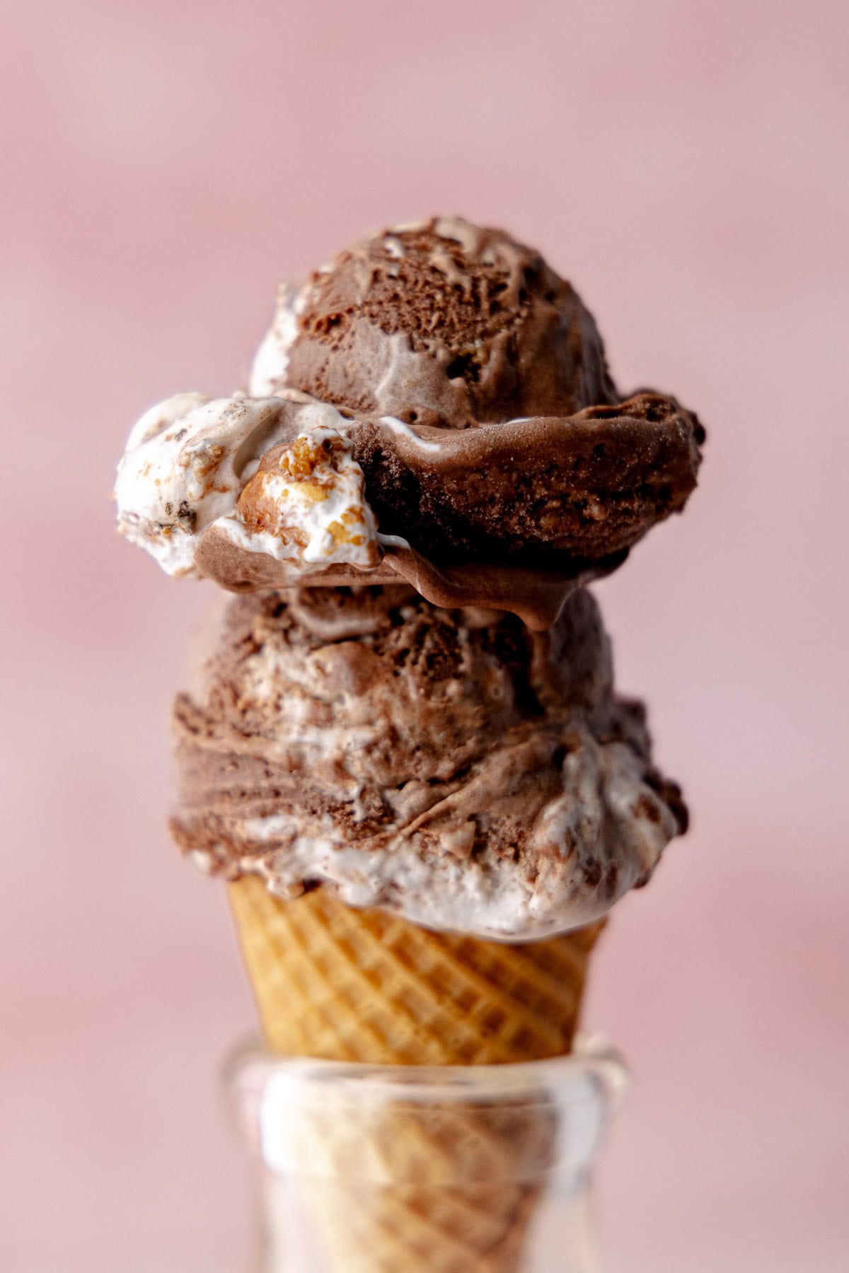 A waffle cone with two scoops of chocolate s'mores ice cream.