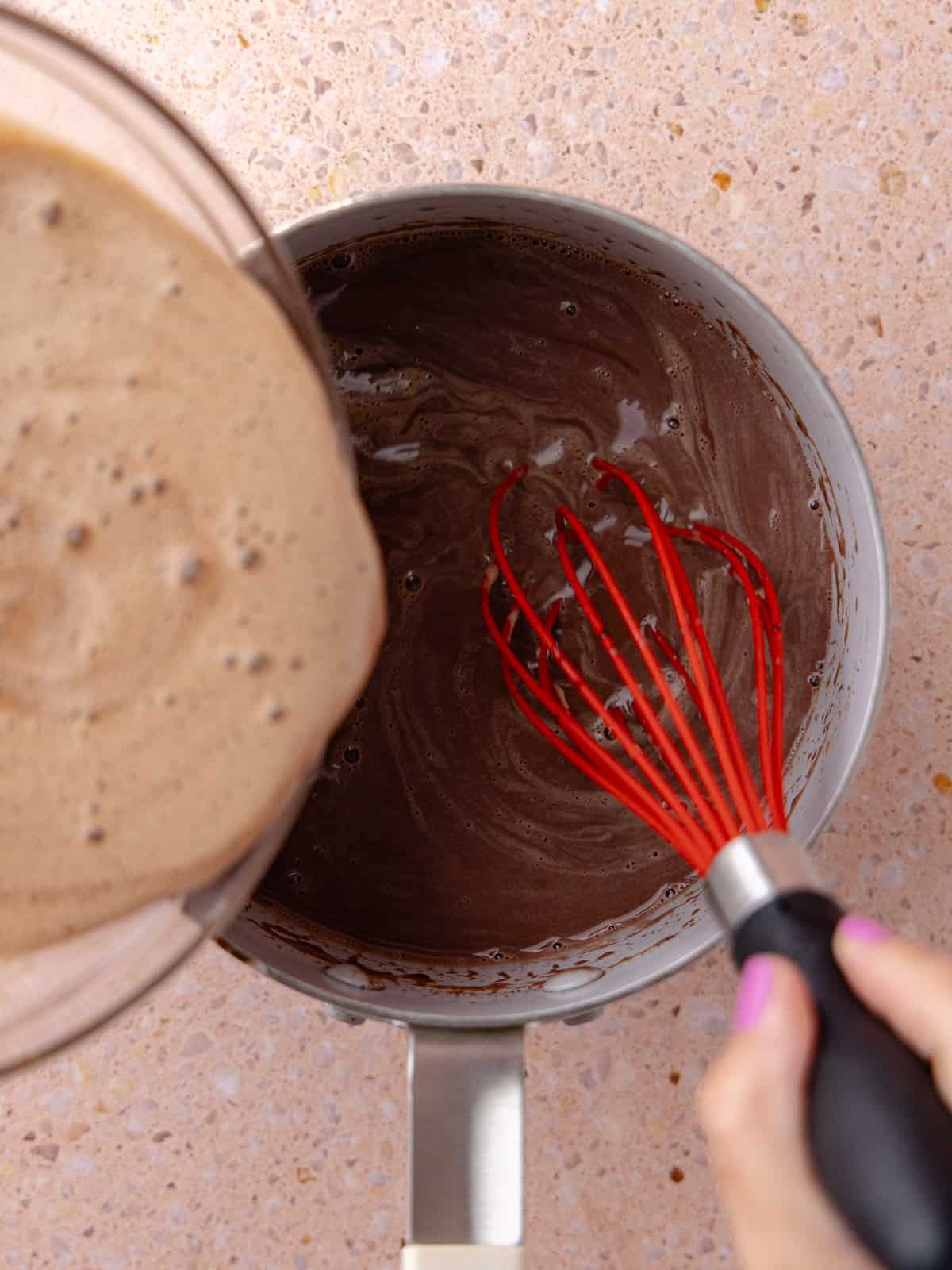 Tempered egg/chocolate is whisked back into the saucepan.