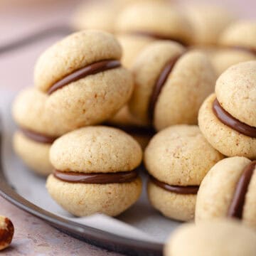 Baci di dama cookies (hazelnut sandwich cookies) are on a serving platter featured photo.
