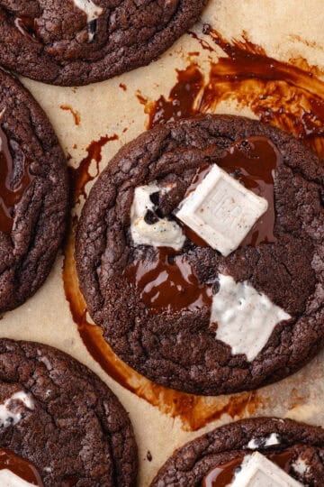 Chocolate cookies and cream cookies are baked and sitting on a parchment paper lined cookies sheet featured photo.