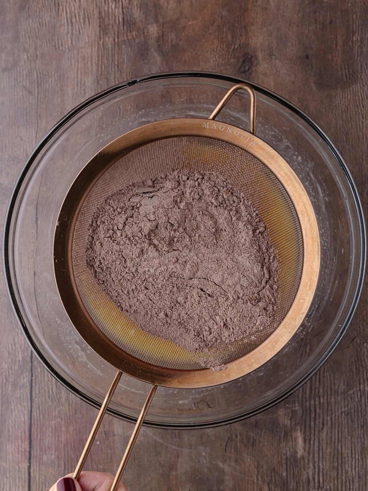 Flour mixture is sifted into the large bowl of wet ingredients.