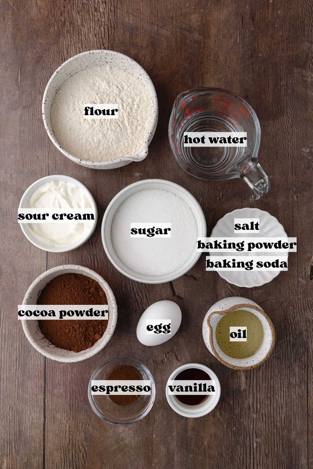 Dark chocolate cake ingredients which include, flour, cocoa powder, espresso powder, baking powder, baking soda, salt, sugar, oil, sour cream, egg, vanilla extract and hot boiling water.