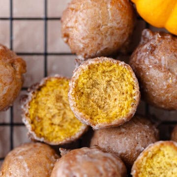 Pumpkin donut holes dipped with a maple glaze are sitting on a wire rack featured photo.