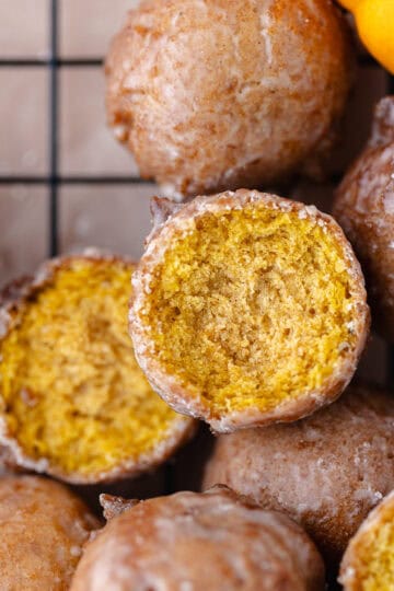 Pumpkin donut holes dipped with a maple glaze are sitting on a wire rack featured photo.
