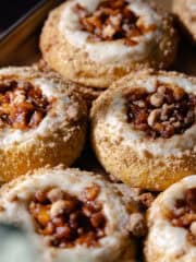 Apple cheesecake brioche buns filled with cheesecake filling, cinnamon apple pie filling and buttery streusel topping are sitting on a baking sheet feature photo.