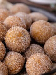 Baked chai donut holes coated in cinnamon sugar are sitting in a serving tray feature photo.