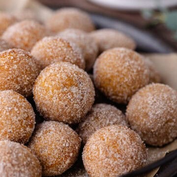 Baked chai donut holes coated in cinnamon sugar are sitting in a serving tray feature photo.