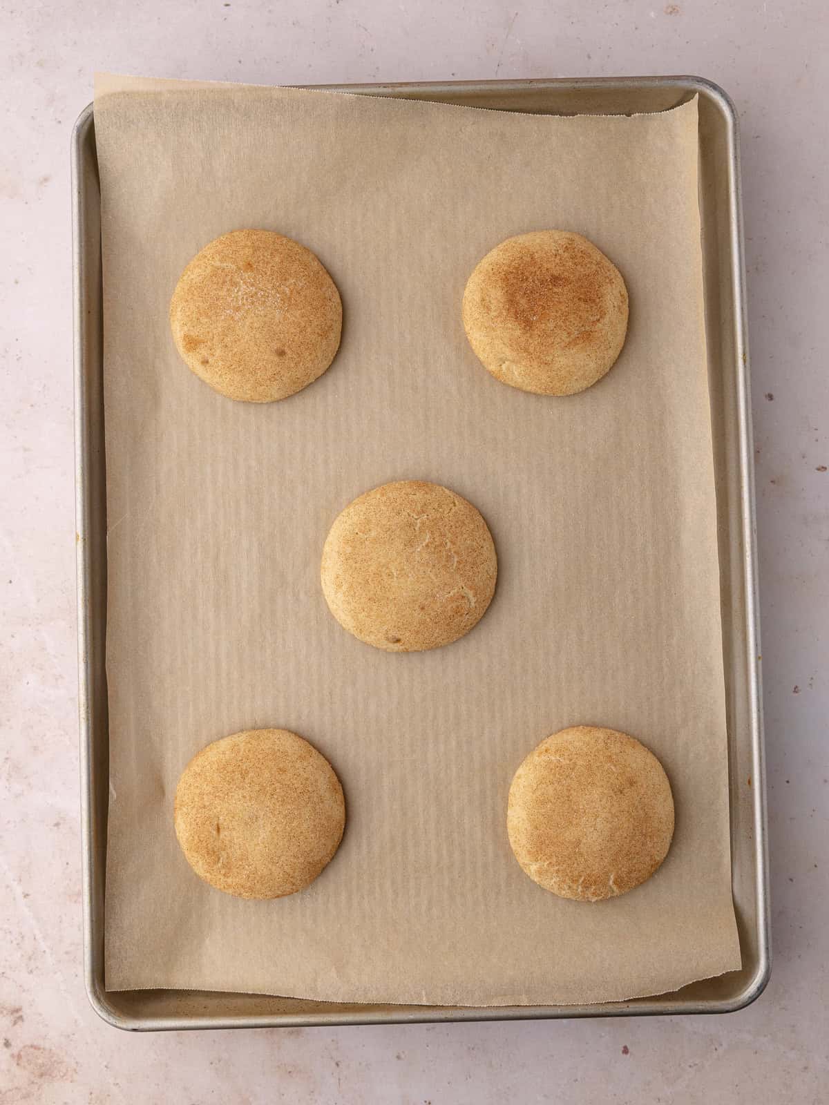 Gooey Biscoff stuffed snickerdoodle cookies are on a baking sheet.