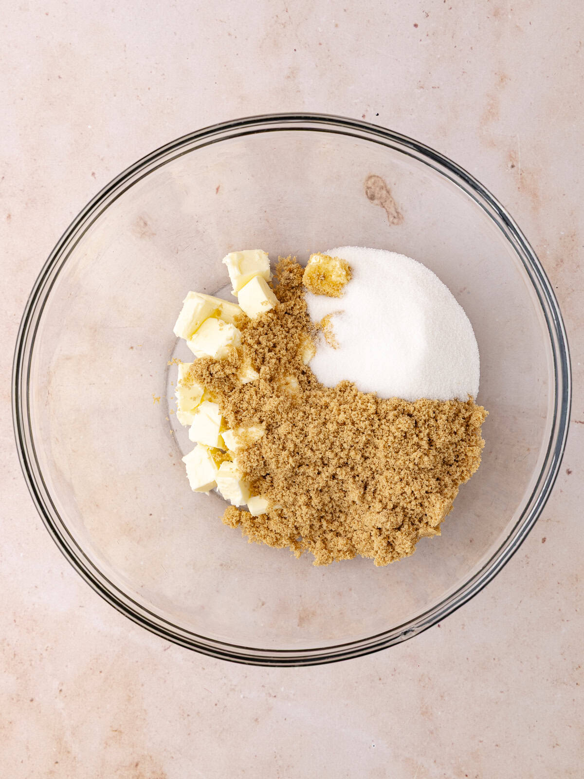 Softened butter, white sugar and brown sugar is in a large glass bowl.
