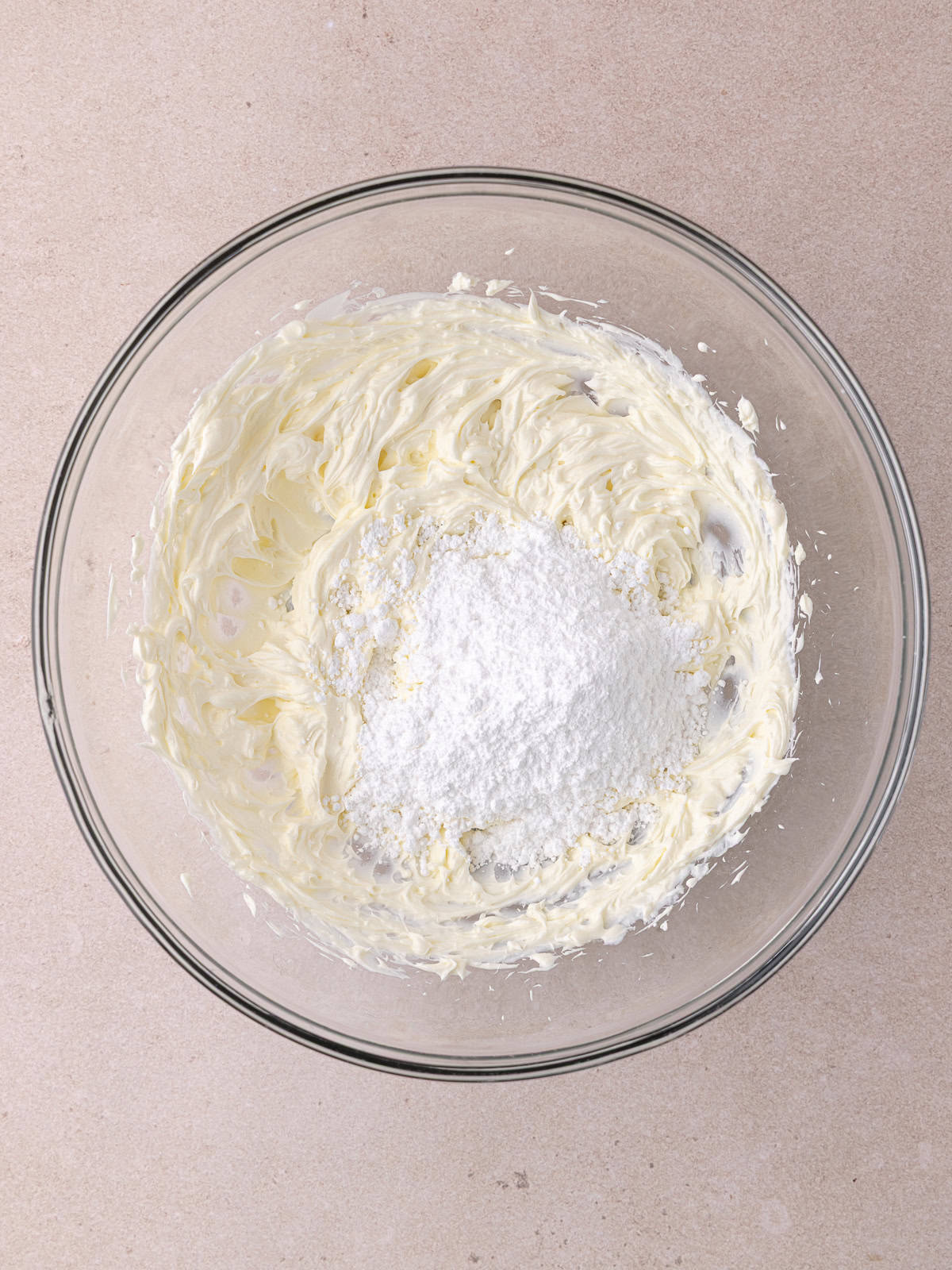 Cream cheese and powdered sugar is whipped together in a large mixing bowl.