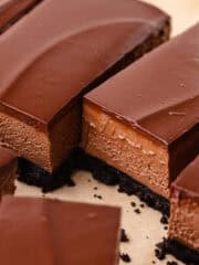 No bake chocolate mousse bars with an oreo cookie crust and chocolate ganache are sliced into bars.