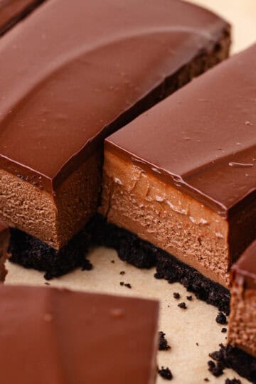 No bake chocolate mousse bars with an oreo cookie crust and chocolate ganache are sliced into bars.