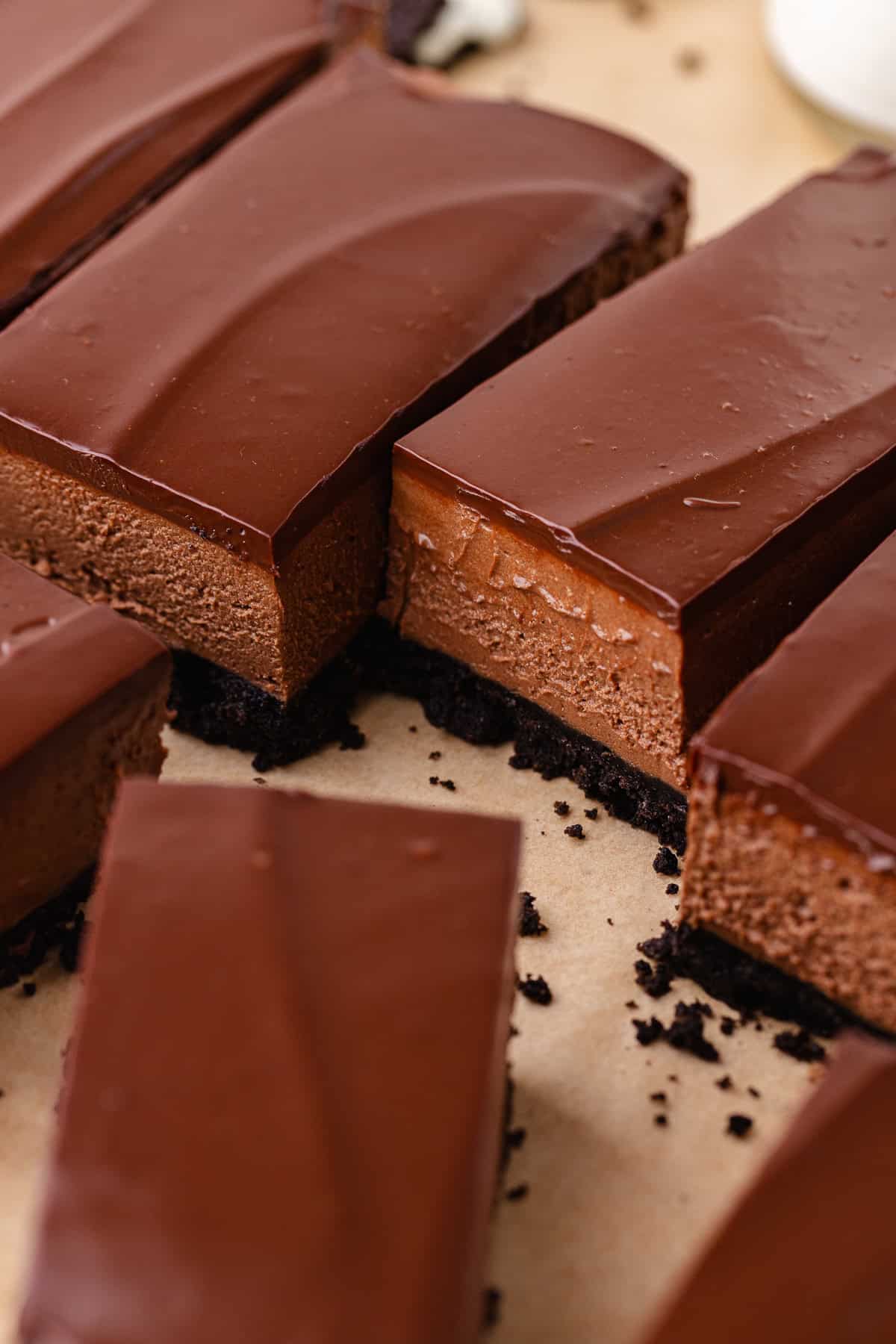 No bake chocolate mousse bars with an oreo cookie crust and chocolate ganache are sliced into bars.