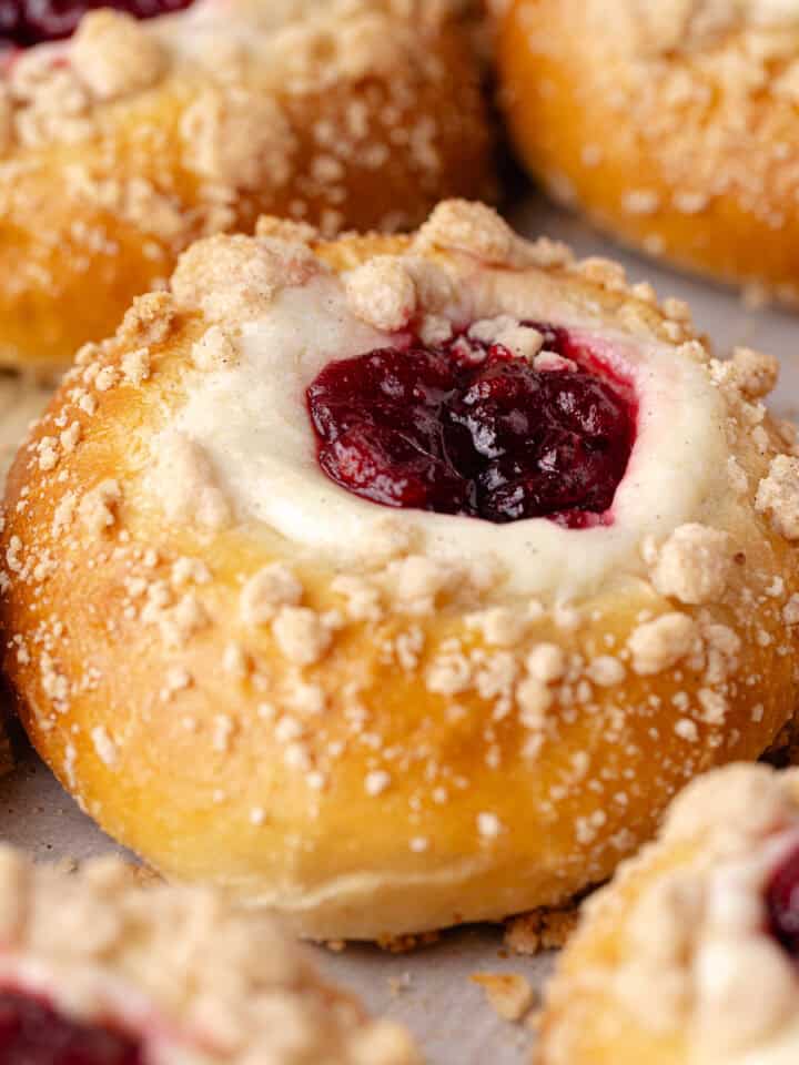 Cranberry cheesecake buns are made with a tangzhong milk bread dough, then filled with a vanilla cheesecake cream, cranberry orange jam and baked with a buttery cinnamon streusel topping featured photo.