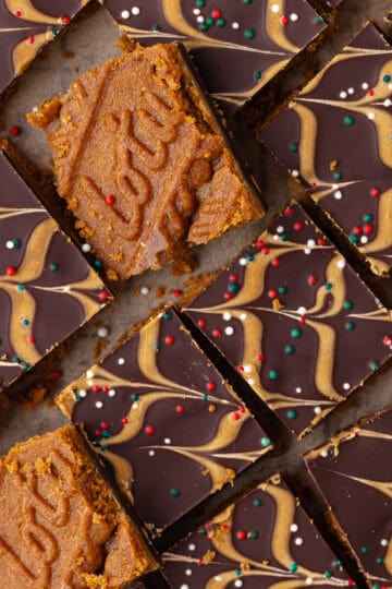 Biscoff toffee candy, also known as Biscoff Christmas crack, is layered with Biscoff cookies, salted toffee, dark chocolate, Biscoff cookie butter and Christmas sprinkles and cut into small squares.