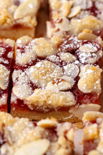 Strawberry crumble bars features a buttery shortbread crust, followed by a layer of homemade strawberry jam, shortbread crumbs, sliced almonds and then finished with a dusting of powdered sugar and cut into squares.