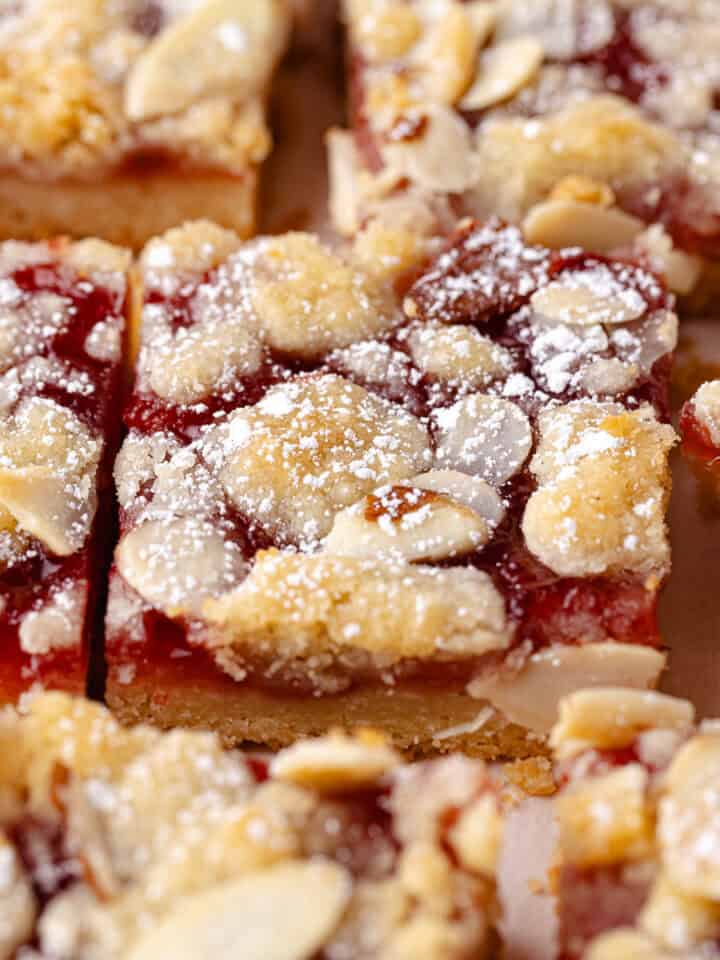 Strawberry crumble bars features a buttery shortbread crust, followed by a layer of homemade strawberry jam, shortbread crumbs, sliced almonds and then finished with a dusting of powdered sugar and cut into squares.
