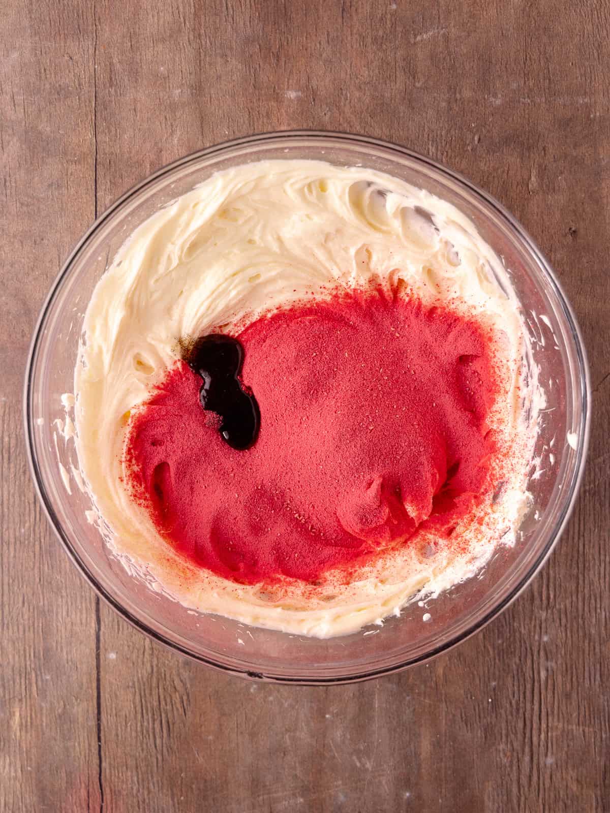 Whipped cream cheese, powdered sugar, sifted freeze-dried raspberry powder and vanilla is in a large mixing bowl.