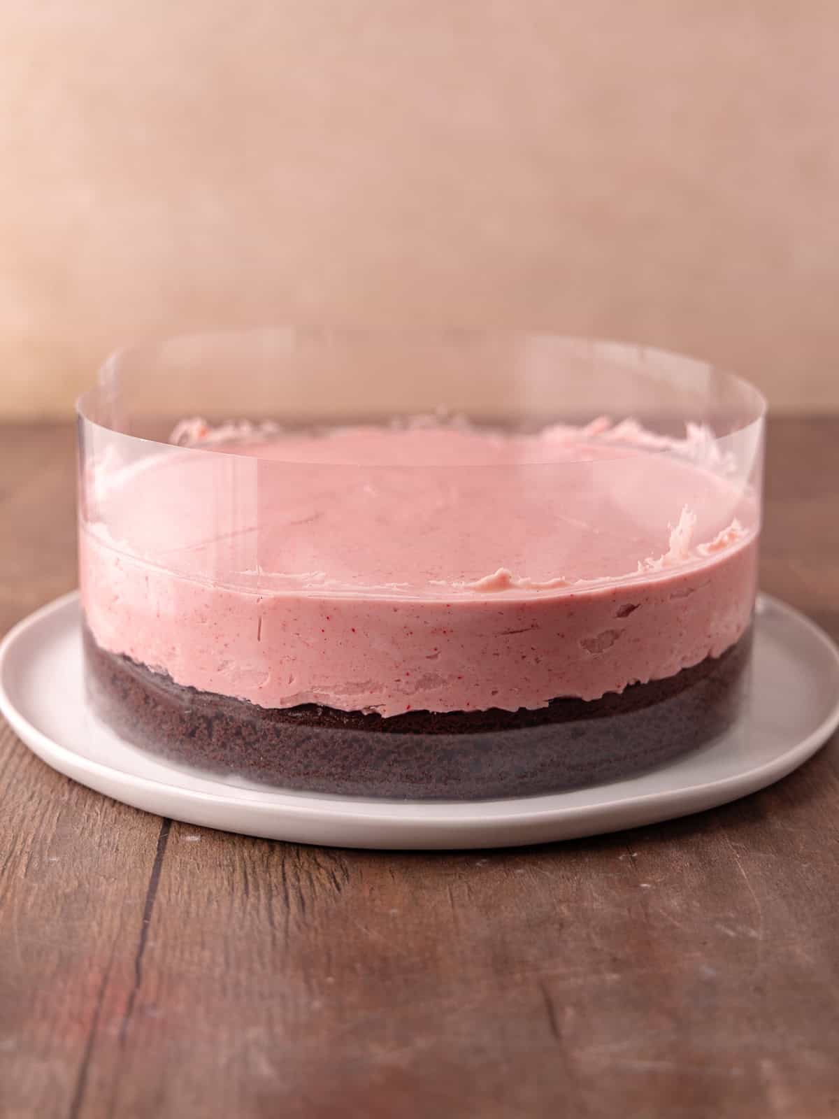 Raspberry white chocolate mousse is spread on top of the chocolate cake layer.