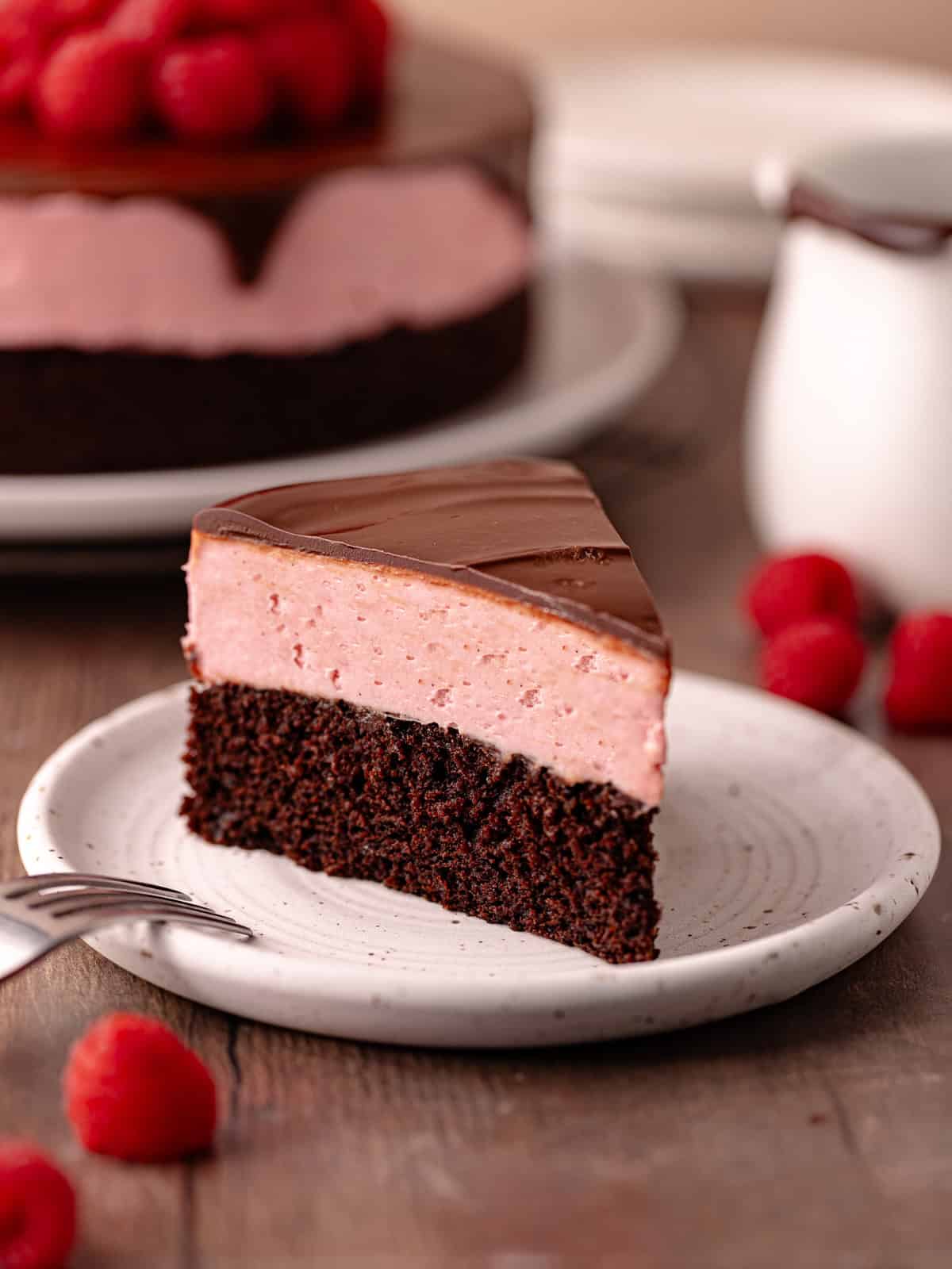Raspberry white chocolate mousse cake features a dark chocolate cake base, followed by a raspberry white chocolate mousse that's made without gelatin or eggs, and finished with a chocolate ganache.
