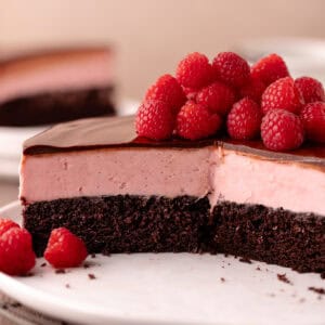 Raspberry white chocolate mousse cake features a dark chocolate cake base, followed by a raspberry white chocolate mousse that's made without gelatin or eggs, and finished with a chocolate ganache.