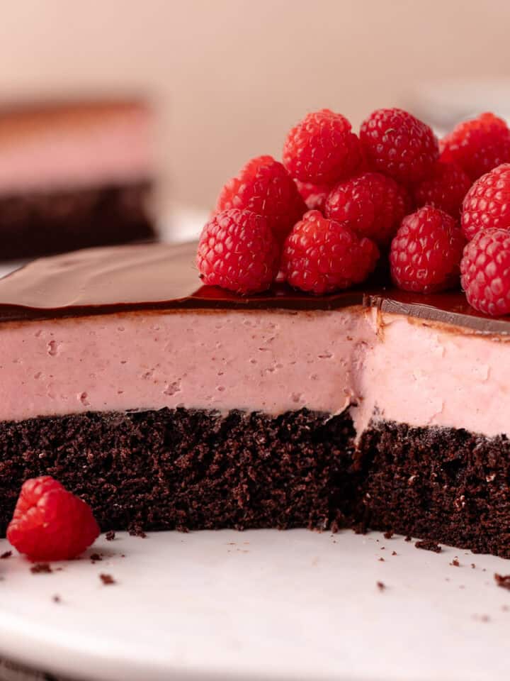 Raspberry white chocolate mousse cake features a dark chocolate cake base, followed by a raspberry white chocolate mousse that's made without gelatin or eggs, and finished with a chocolate ganache.