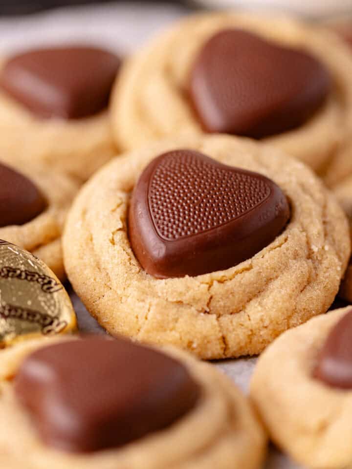 Super soft and moist peanut butter thumbprint cookies, also known as peanut butter blossom cookies are rolled in sugar and pressed with Reese's hearts peanut butter cups.