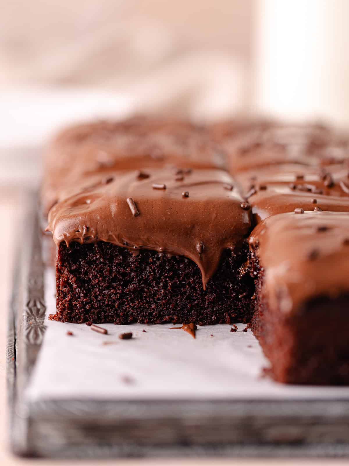 Soft and moist chocolate malted cake is topped with chocolate malted frosting and chocolate sprinkles.