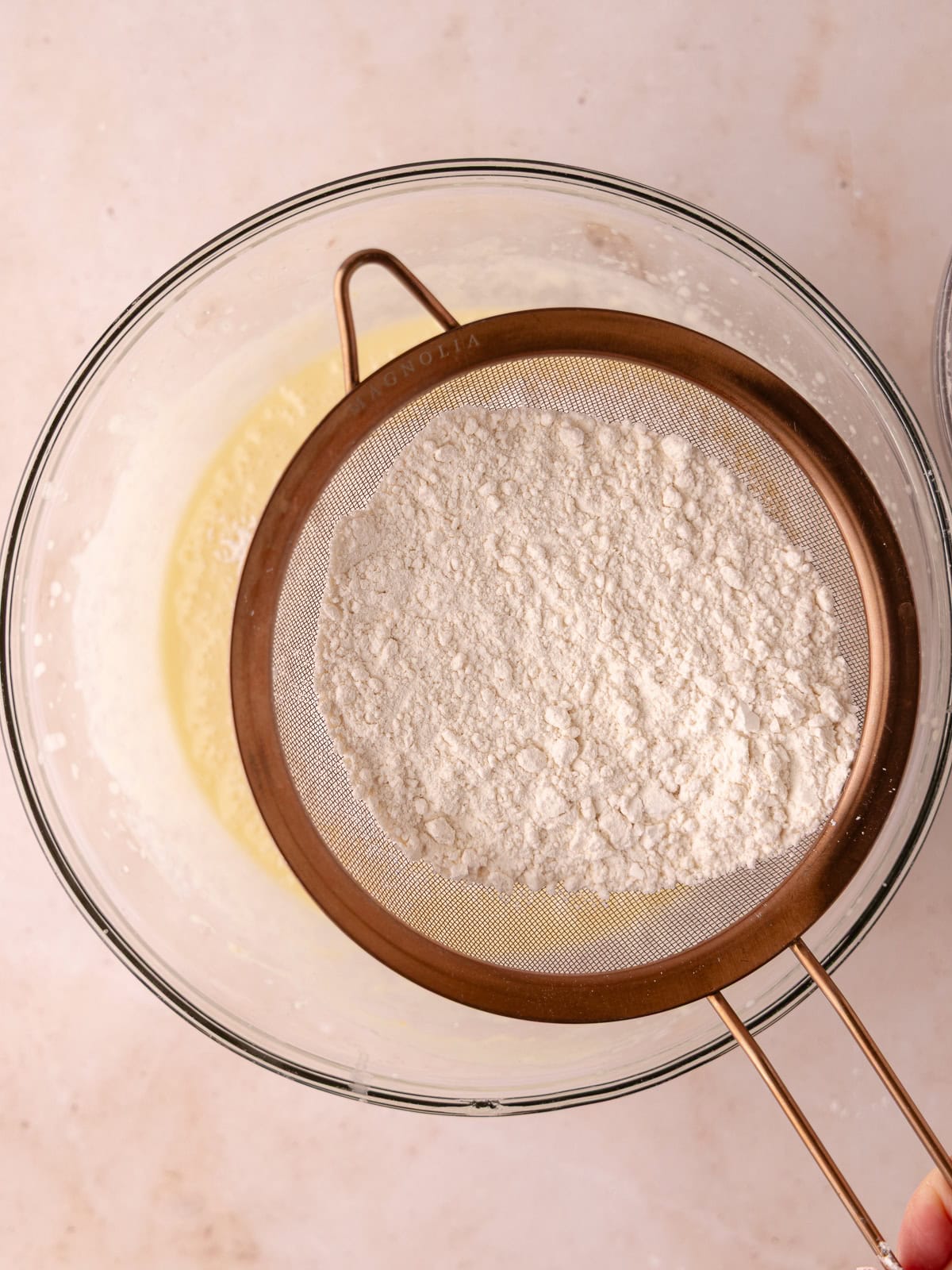 Flour mixture is sifted into the wet ingredients.