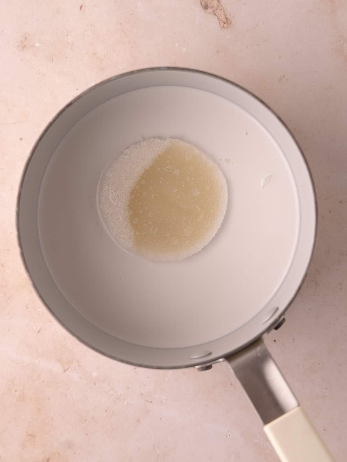 Bloomed gelatin is added to a small pot with canned coconut milk.