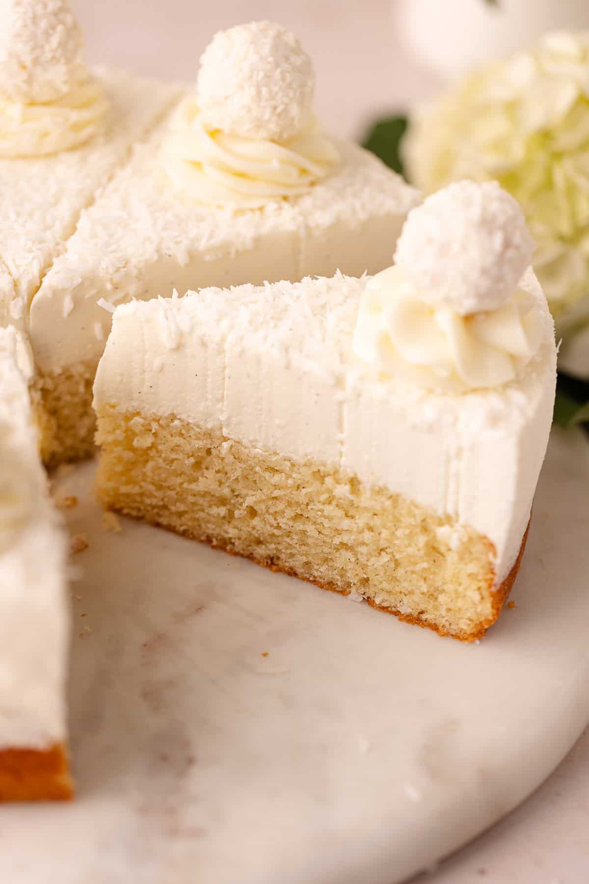 Dreamy coconut mousse cake featuring a super moist coconut cake base, layered with a light and creamy coconut mousse, shredded coconut and Raffaello candy!