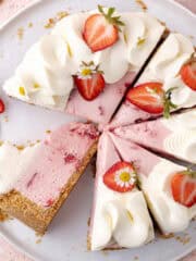 No bake strawberry pretzel cheesecake decorated with whipped cream and strawberries are sliced on a serving plate feature photo.