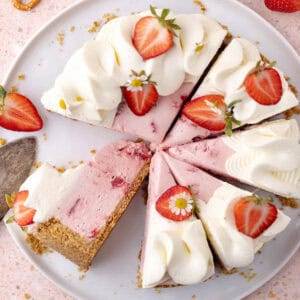 No bake strawberry pretzel cheesecake decorated with whipped cream and strawberries are sliced on a serving plate feature photo.