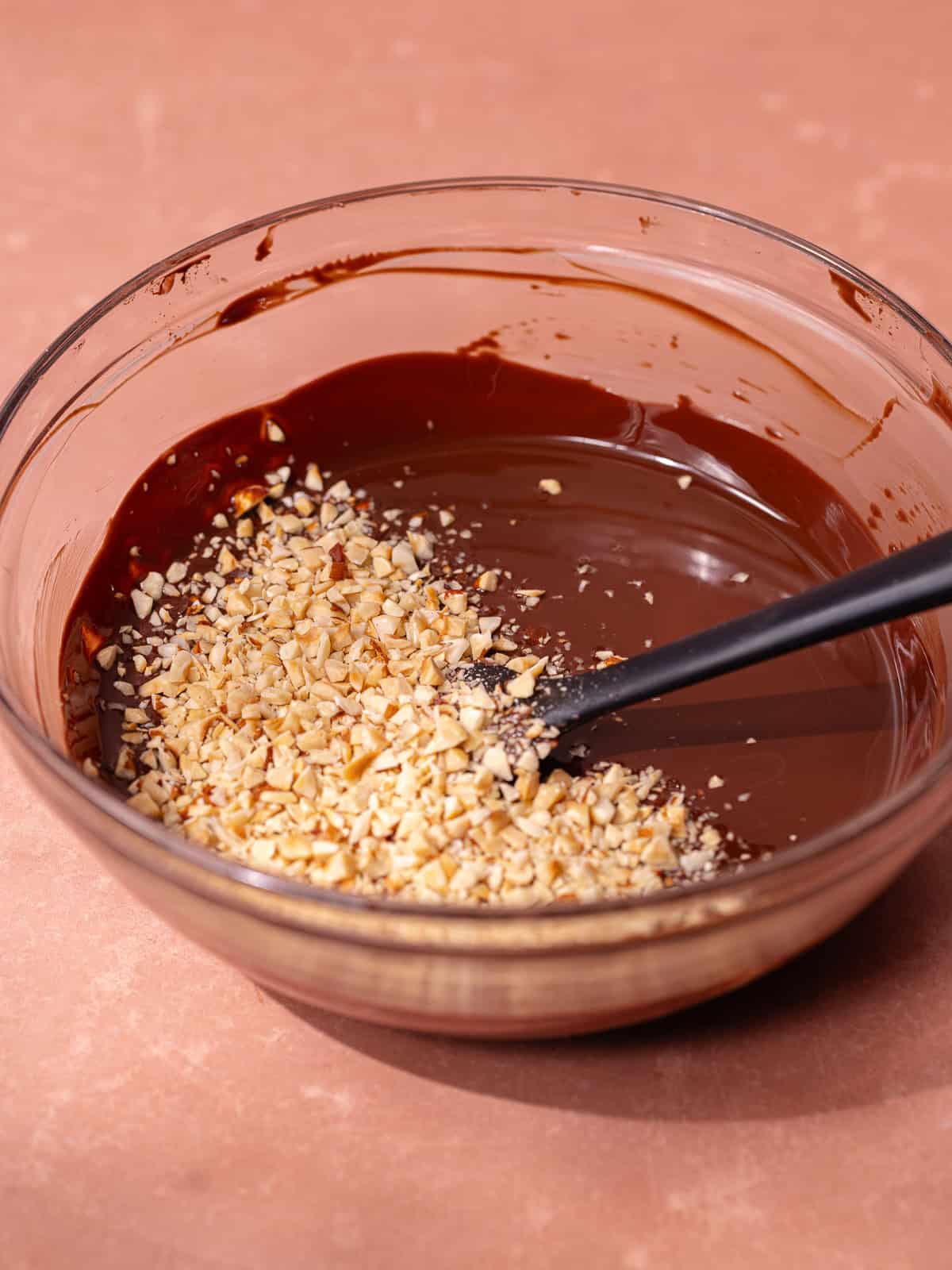 Melted chocolate and finely chopped hazelnuts are in a small mixing bowl.