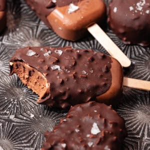 Magnum style super creamy chocolate coconut popsicles are dipped in a hazelnut chocolate magic shell and topped with flaky sea salt.