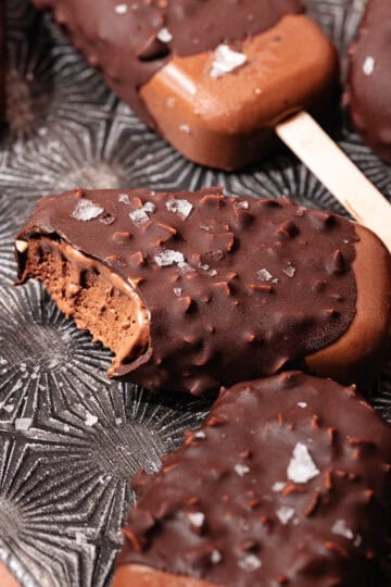 Magnum style super creamy chocolate coconut popsicles are dipped in a hazelnut chocolate magic shell and topped with flaky sea salt.
