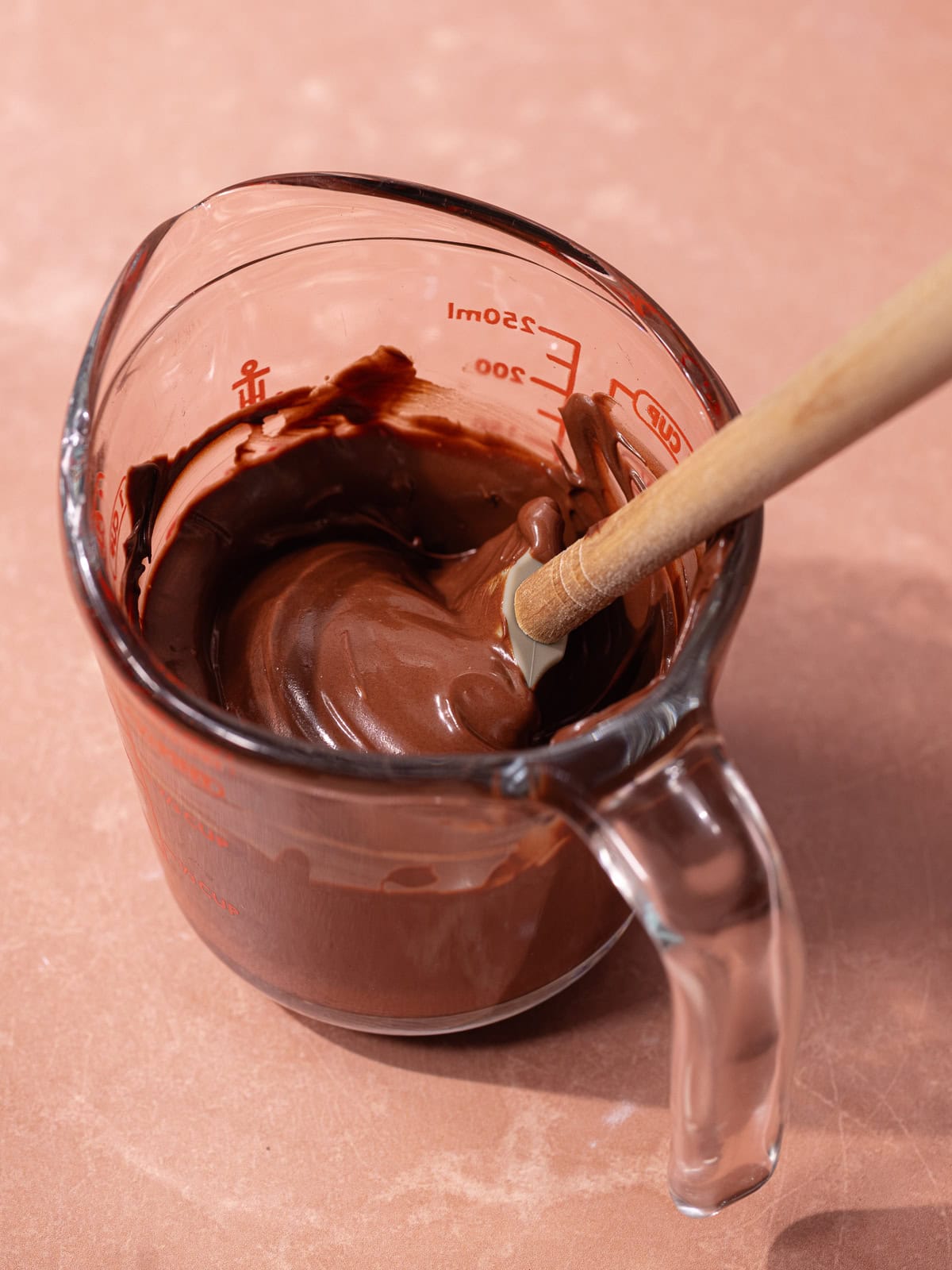 Semi-sweet chocolate chips are melted in a glass measuring cup.
