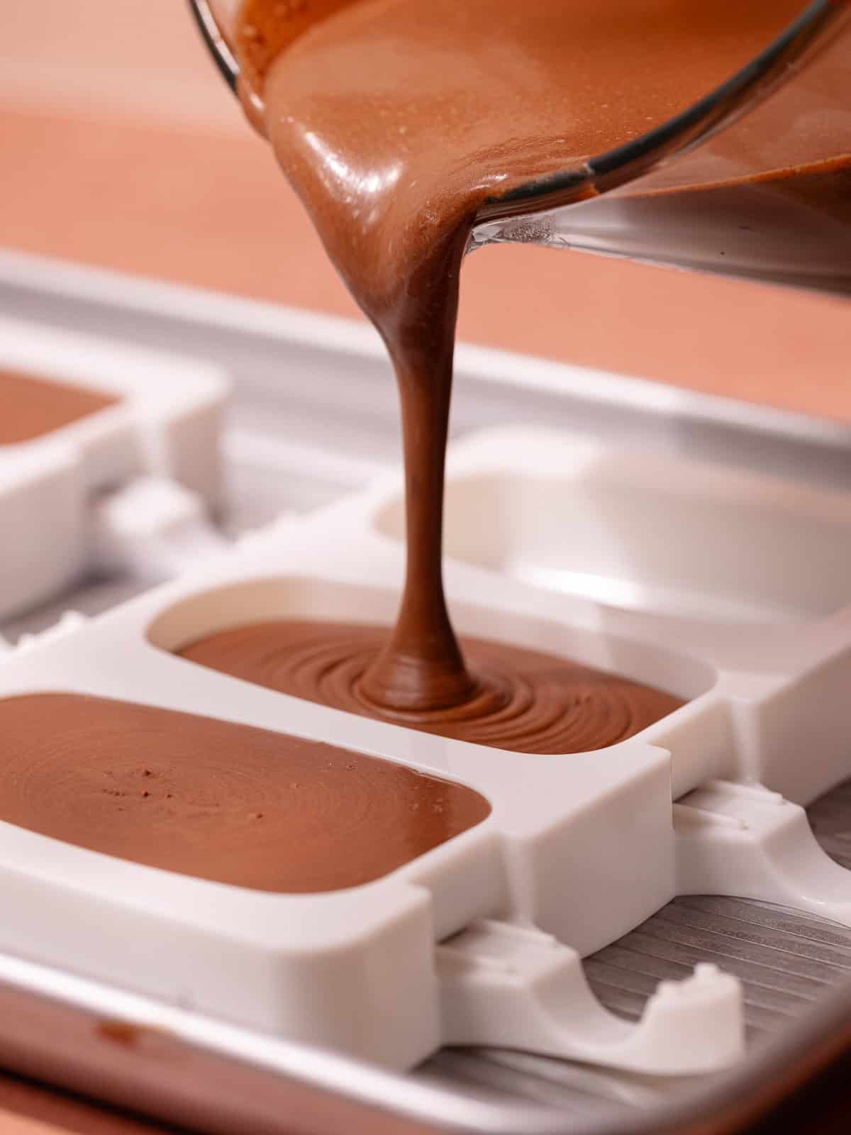 The chocolate coconut ice cream base is poured into popsicle molds.