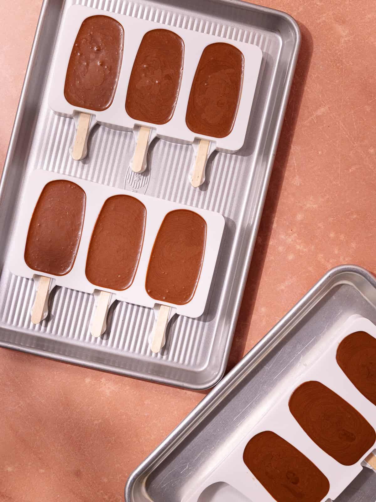 The chocolate coconut ice cream base is poured into popsicle molds.