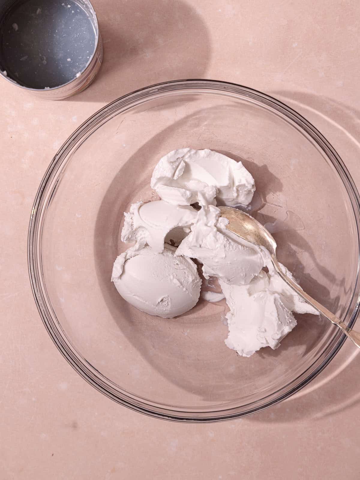 Coconut cream is scooped into a glass bowl, separating the cream from the coconut water.