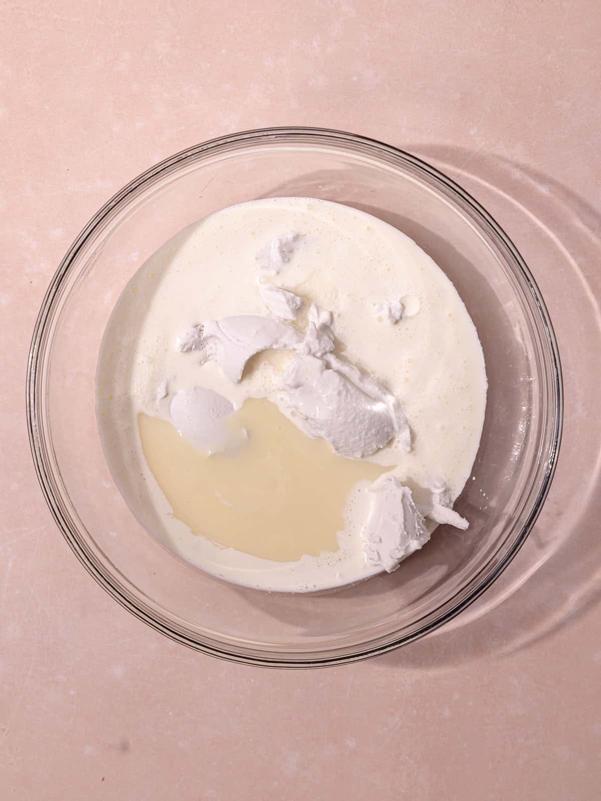 The coconut cream, cold heavy cream, sweetened condensed milk and coconut extract are in a glass mixing bowl.
