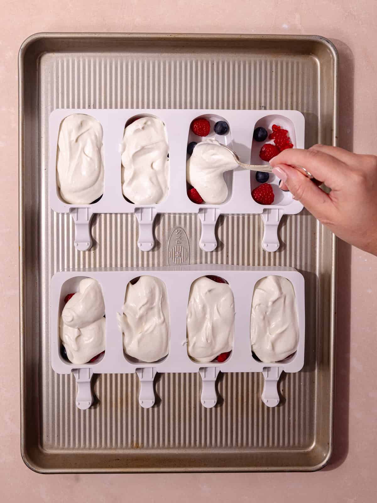 The no-churn coconut ice cream is scooped into the popsicle molds.