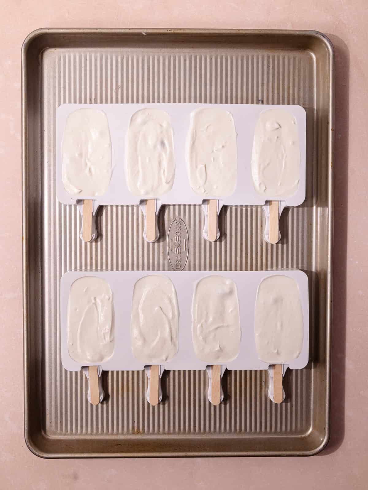 Wooden popsicle sticks are inserted into the popsicle molds and is ready to freeze.