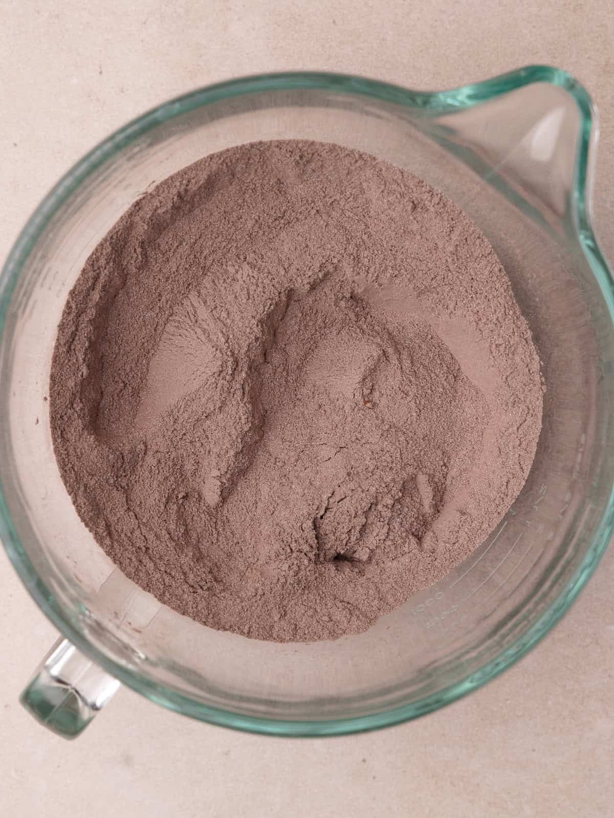 Sugar, sifted flour, cocoa powder, baking powder, baking soda and salt are whisked together until well combined in the bowl of a stand mixer.